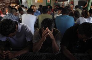 Un grupo de inmigrantes deportados rezan y agradecen por los alimentos recibidos gracias a la Iniciativa Kino, en Nogales, Sonora. Foto: AP