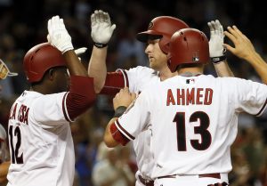 Arizona Diamondbacks Mark Trumbo greets teammates Nick Ahmed (13) and Rubby De La Rosa (12) at home plate after Trumbo hit a three run home run against the Washington Nationals during the fourth inning of a baseball game, Tuesday, May 12, 2015, in Phoenix. (AP Photo/Matt York)