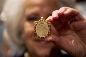 La asistente de galería Sandra Handley posa para fotógrafos con un mechón de pelo de Wolfgang Amadeus Mozart, contenido en un relicario dorado del siglo XIX, el martes 26 de mayo del 2015 en la casa de subastas Sotheby's en Londres. El mechón podría facturar hasta 12.000 libras esterlinas (más de $18.000 dólares) el jueves en la venta de música, libros y manuscritos continentales y rusos de la rematadora. (AP Foto/Matt Dunham)