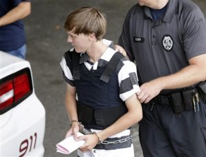 Dylann Storm Roof es custodiado por agentes al salir de la Corte del condado Cleveland en Shelby, Carolina del Norte, el jueves 18 de junio de 2015. Roof es señalado como el responsable de abrir fuego con una pistola contra varias personas negras y matar a nueve de ellas en la Iglesia Episcopal Metodista Africana Emanuel en Charleston, la noche del miércoles. (AP Foto/Chuck Burton)