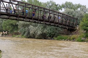 Varias personas observan el Río Animas desde un puente mientras aguas residuales de color mostaza mezcladas con metales pesados fluyen en la corriente en el Parque Berg en Farmington, Nuevo México. Foto: AP