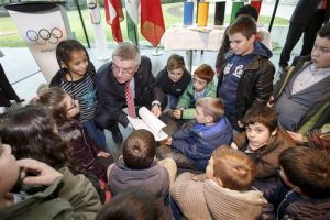 El presidente del COI, Thomas Bach, centro, habla con niños antes de una ceremonia para poner en marcha la construcción la nueva sede del COI. Foto: AP