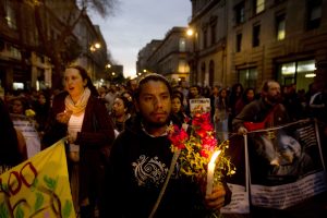 Un hombre sostiene flores y una veladora durante una marcha en la Ciudad de México por los 16 meses de la desaparición de 43 estudiantes de la Normal de Ayotzinapa. Foto: AP