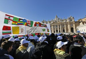 Fieles reunidos cerca de una pancarta adornada con las banderas de varios países y un mensaje escrito que dice: Gracias Papa Francisco, aguardan el inicio de la misa del Angelus en la Plaza de San Pedro. Foto: AP