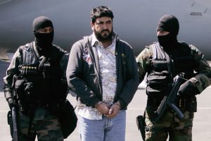 En esta imagen del 21 de enero de 2008, agentes de la policía federal mexicana escoltan a Alfredo Beltrán Leyva "El Mochomo" luego de su arresto y llegada al aeropuerto de la Ciudad de México. Leyva, acusado líder de un cártel de narcotráfico que de acuerdo a las autoridades alguna vez mantuvo una estrecha relación con Joaquín "El Chapo" Guzmán, se declaró culpable en una corte federal de Washington el 23 de febrero de 2016. y admitió que ayudó a traficar toneladas de cocaína de sudamérica a Estados Unidos. (Foto AP/Eduardo Verdugo, Archivo)