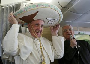 El papa Francisco se pone un sombrero mexicano a bordo del avión de Roma a La Habana, una escala camino de México, donde pasará una semana, viernes 12 de febrero de 2016. En la capital cubana el pontífice espera encontrarse con el jefe de la Iglesia Ortodoxa Rusa, patriarca Kirill, en lo que el Vaticano considera un paso histórico para sanar 1.000 años de cisma cristiano. A la derecha, el vocero vaticano Federico Lombardi (Alessandro Di Meo/Pool Photo via AP)