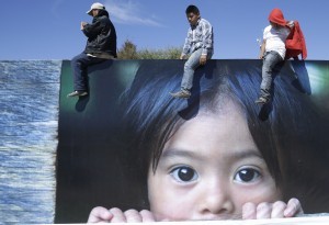 Tres personas desde lo alto de un gran cartel escuchan al papa Francisco que oficia una misa en San Cristóbal de las Casas, México, el lunes 15 de febrero de 2016. Francisco celebró la cultura indígena mexicana con una visita al estado de Chiapas, con una misa en tres idiomas nativos gracias a un nuevo decreto vaticano que aprobó su uso en la liturgia. (Foto AP/Gregorio Borgia)