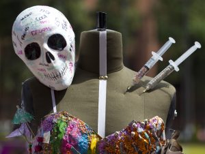 Una calavera de plástico y unas jeringas decoran un maniquí que sostiene un vestido durante una competencia estudiantil de diseño de modas inspirada en los efectos del narcotráfico en la cultura mexicana, realizada en la Universidad Iberoamericana en la Ciudad de México el miércoles 16 de marzo de 2016. (Foto AP/Rebecca Blackwell)