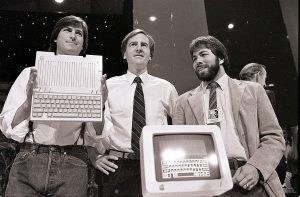 ARCHIVO - En esta foto de archivo del 24 de abril de 1984, de izquierda a derecha, presidente del directorio y cofundador Steve Jobs, director general John Sculley y cofundador Steve Wozniak presentan la computadora Apple IIc en San Francisco. Al cumplir 40 años, Apple es una empresa muy distinta de la que fundaron Jobs y Wozniak en un garaje de Silicon Valley en 1976. (AP Foto/Sal Veder, File)