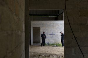 En esta imagen del 3 de julio de 2014 puede verse a policías estatales en el interior de una bodega en la que hay una cruz negra en una pared, cerca de las manchas de sangre dejadas en el suelo tras un tiroteo entre soldados mexicanos y supuestos criminales a las afueras de la localidad de San Pedro Limón en el Estado de México. La principal organización defensora de los derechos humanos de México anunció el miércoles 30 de marzo de 2016 que una corte militar absolvió a seis de los siete soldados acusados de indisciplina por los asesinatos de 2014. (Foto AP/Rebecca Blackwell, archivo)